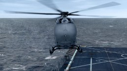 A military gray helicopter hovers over a navy ship's deck at sea. The ocean is expansive, and the sky is overcast. As it prepares to land on the marked area, one could envision future missions enhanced by contracts like the USMC Aerial Logistics Connector Contract awarded to Airbus U.S. Space & Defense.